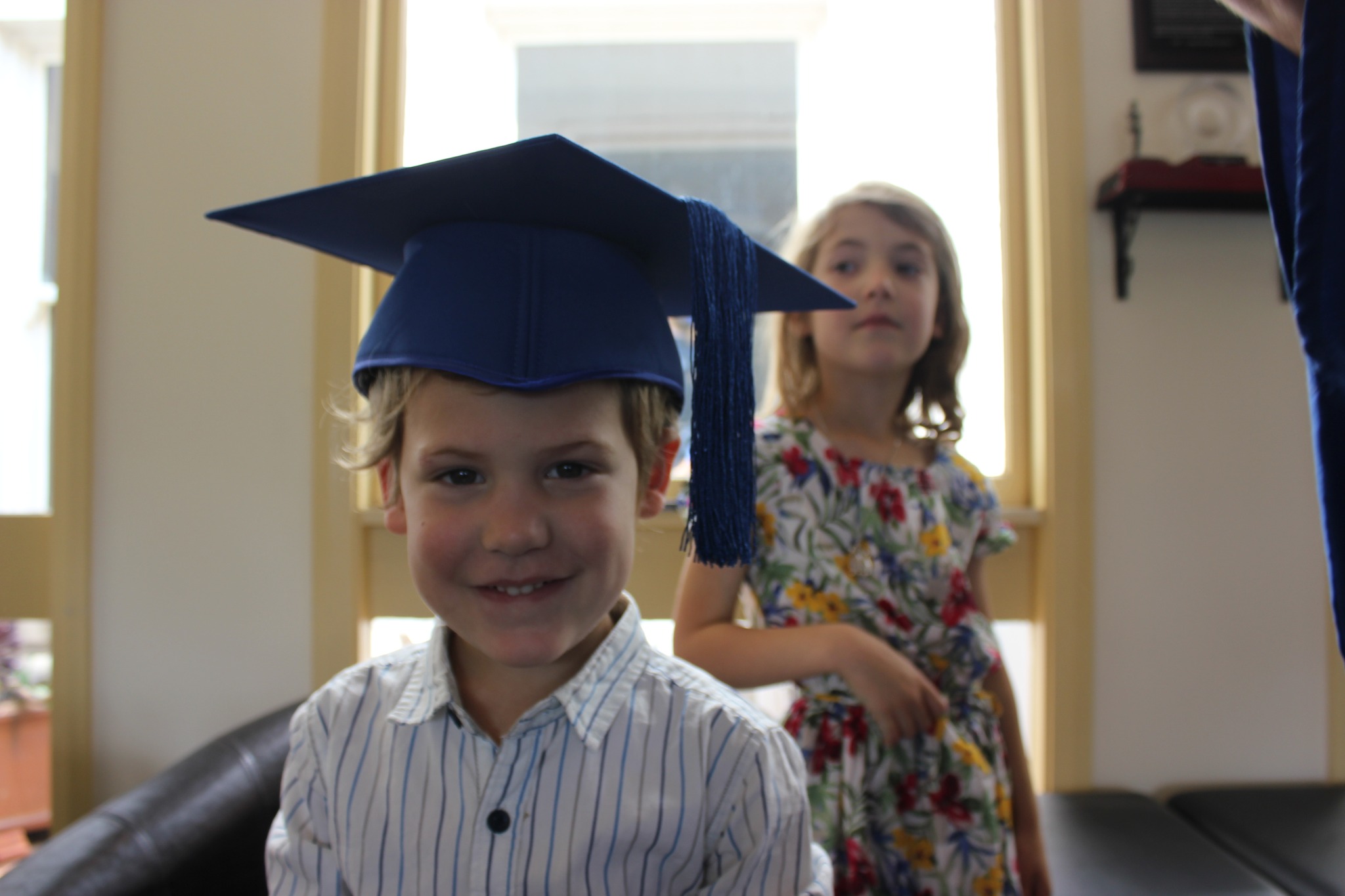 Young mother studying shows Felix wearing a Graduation hat in front of his sister